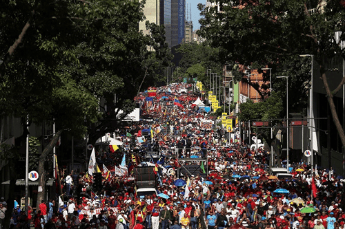 Endless crowded street protest with political flags, banners, and vibrant atmosphere in a busy city.
