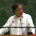 Thoughtful man speaking at a podium with microphones, delivering a speech or presentation.