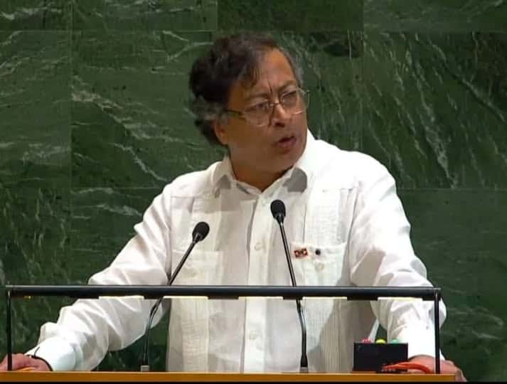 Thoughtful man speaking at a podium with microphones, delivering a speech or presentation.