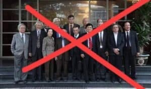 People in formal business attire standing outdoors, with a red X overlay.